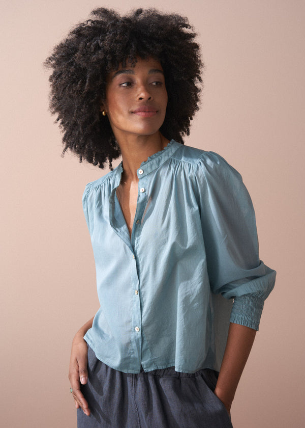 Woman wearing a light blue blouse against a beige background