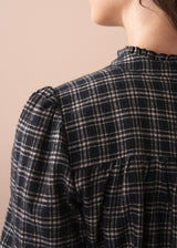 Person wearing a black and white checkered shirt against a beige background