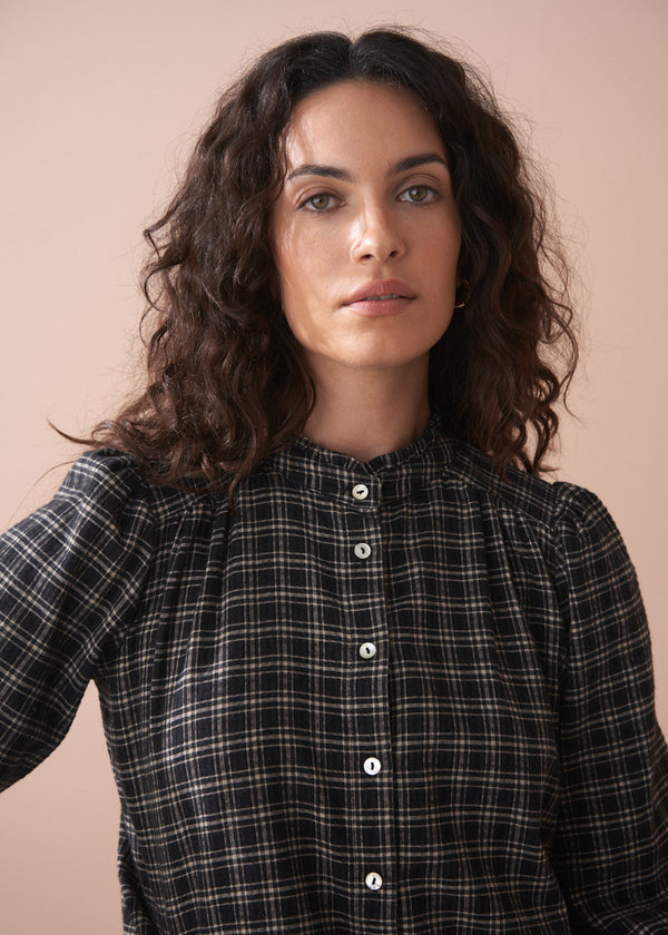 Woman wearing a black and white check shirt against a beige background