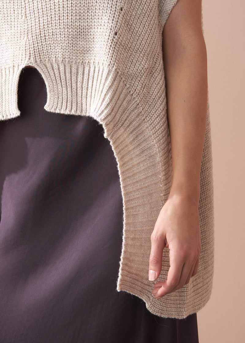 Beige knitted sleeveless top worn by a person against a neutral background