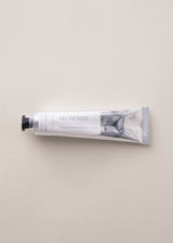 Hand cream tube labeled 'Alchemist' on a light gray background