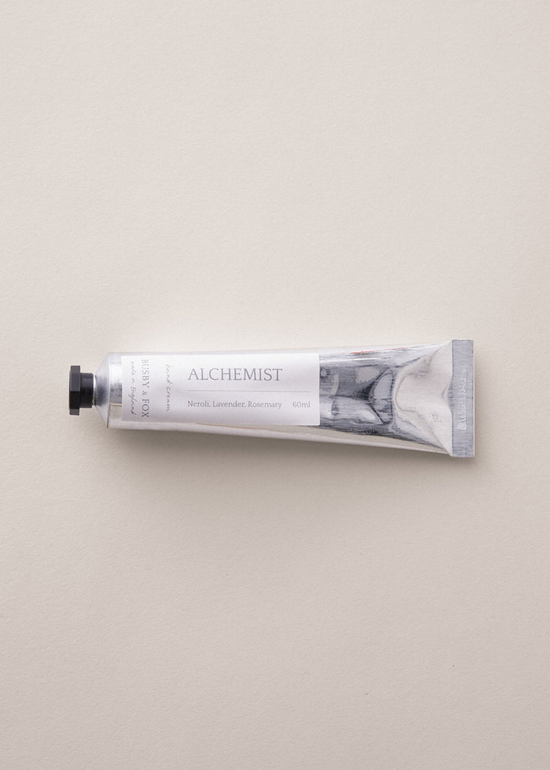 Hand cream tube labeled 'Alchemist' on a light gray background