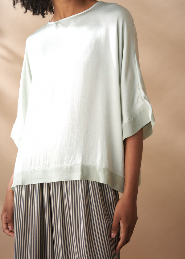Light green top worn by a person on a beige background