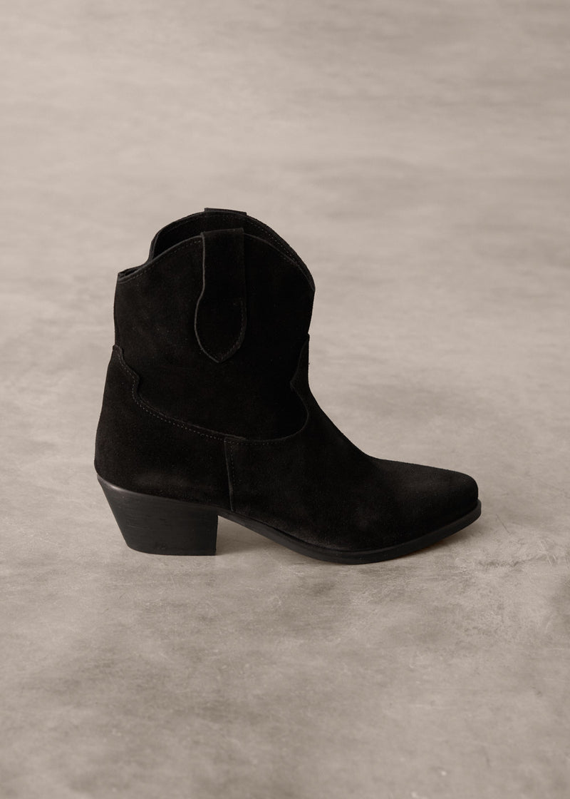 Black suede cowboy boot on a gray background