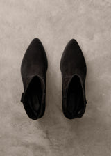 Pair of black ankle boots on a gray concrete surface