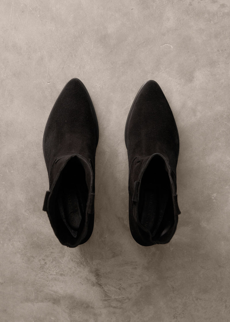 Pair of black ankle boots on a gray concrete surface