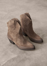 Pair of brown suede boots on a gray concrete surface