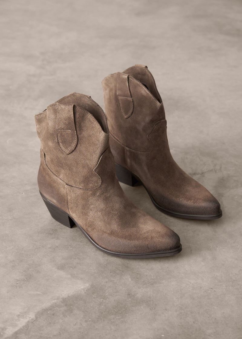 Pair of brown suede boots on a gray concrete surface