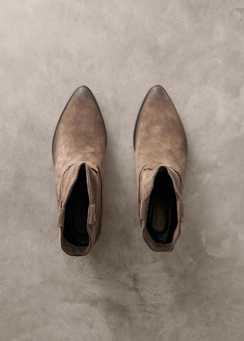 Pair of brown suede ankle boots on a textured gray surface