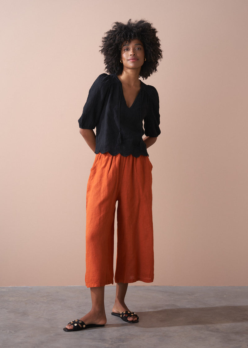 Black embroidered top with scallop hem and tassel details
