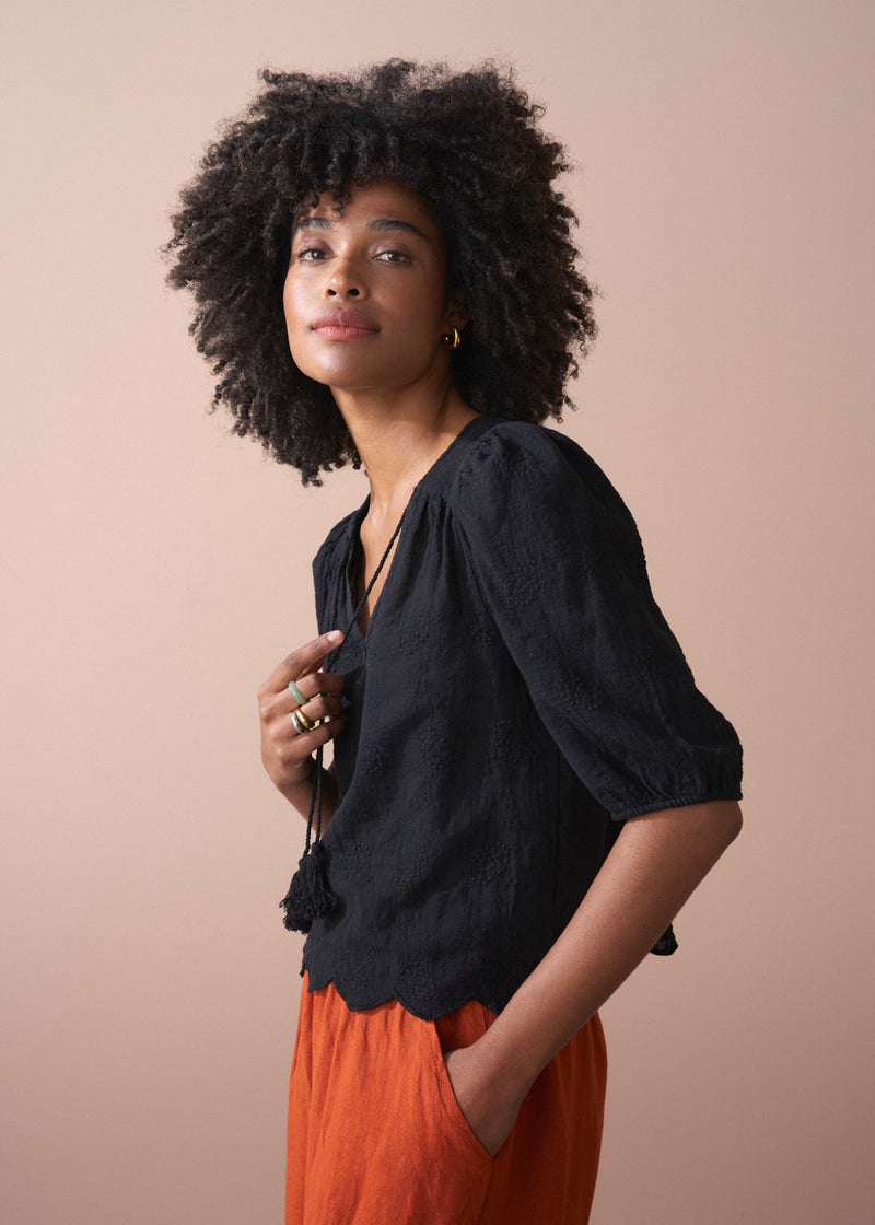 Black embroidered top with scallop hem and tassel details