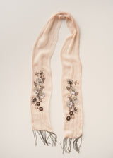 A light peach-pink scarf with fringe ends, featuring vertical floral and leaf embellishments in metallic silver, gold, and brown sequins and beads, laid flat on a light beige background.