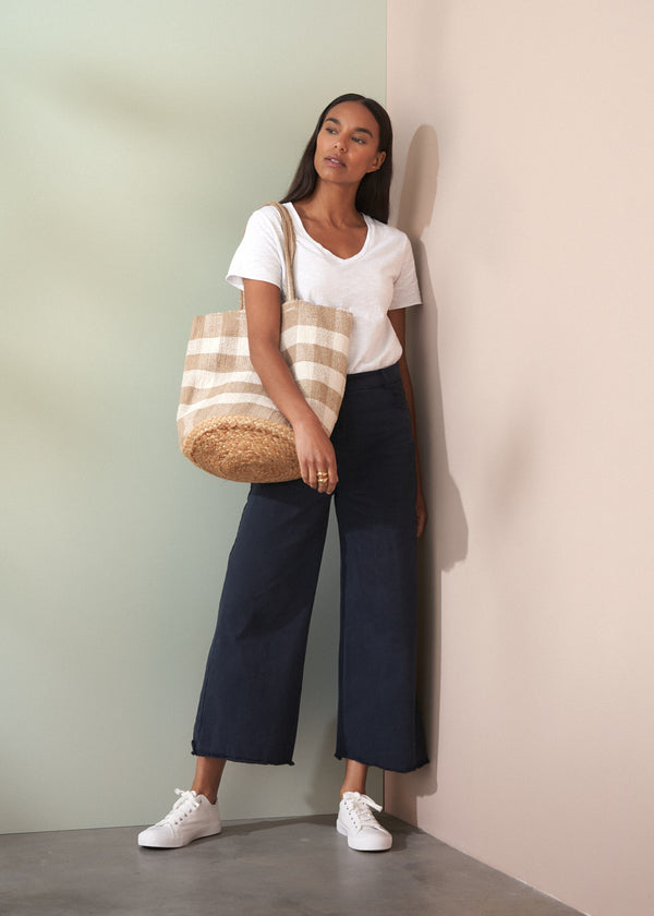 Woman holding a striped tote bag against a neutral wall