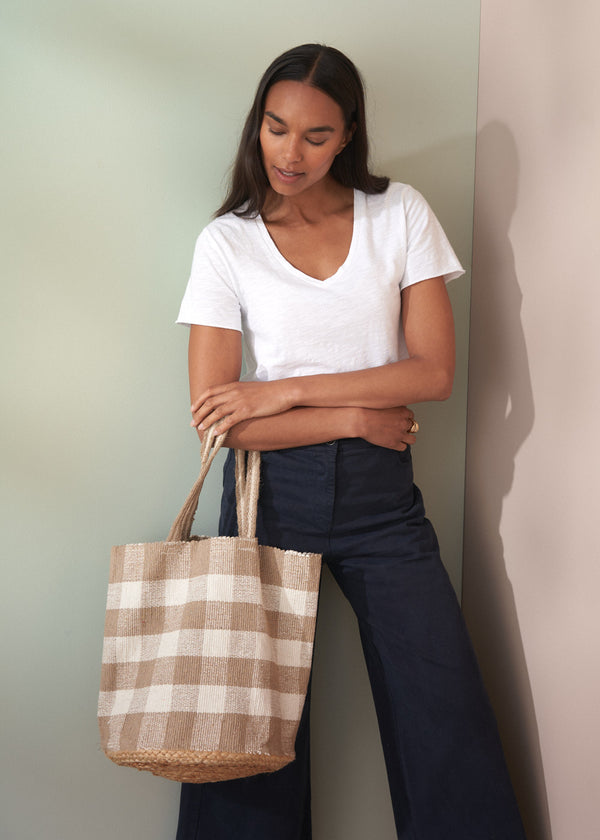 Woman holding a checkered bag against a plain background