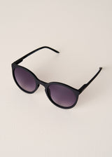 Black sunglasses with dark lenses on a light beige background
