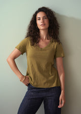 Woman wearing an olive green v-neck cotton t-shirt with blue jeans