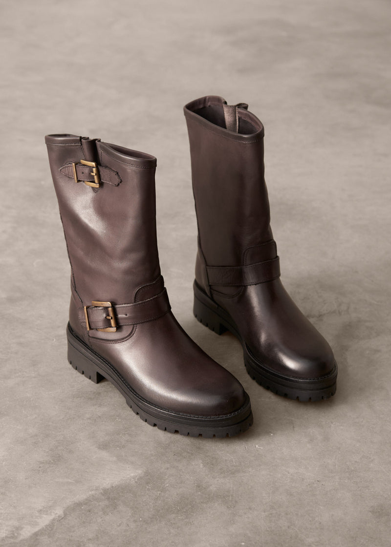 Pair of brown leather boots with buckles on a gray surface