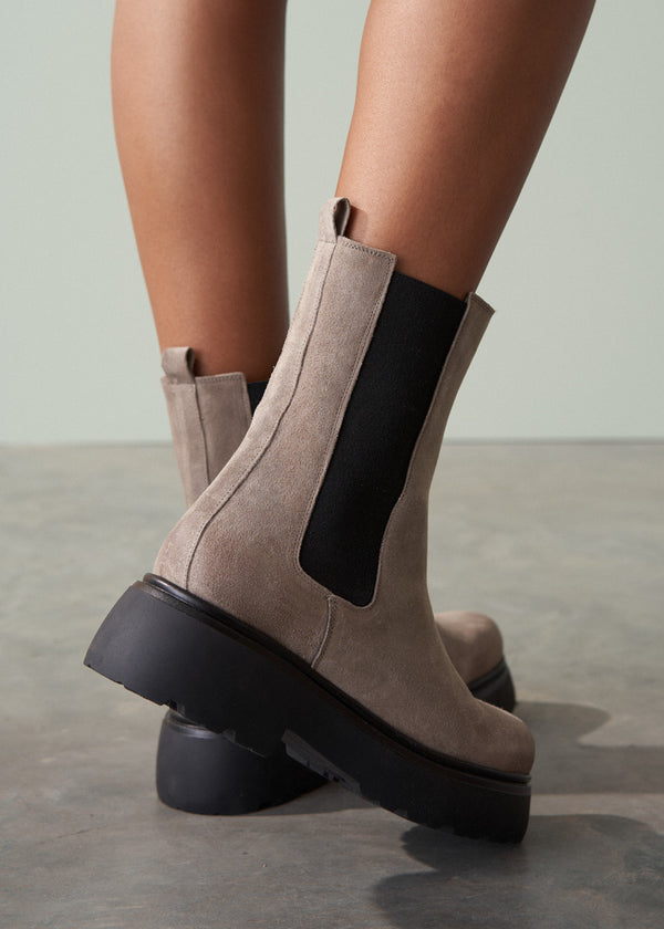 Brown suede platform boots with black soles on a neutral background