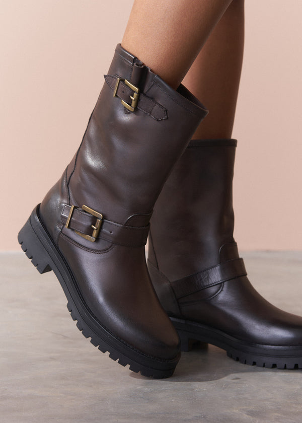 Brown leather boots with buckles on a neutral background