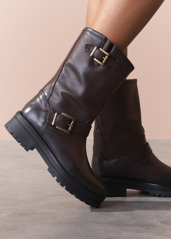 Brown leather boots with buckles on a neutral background