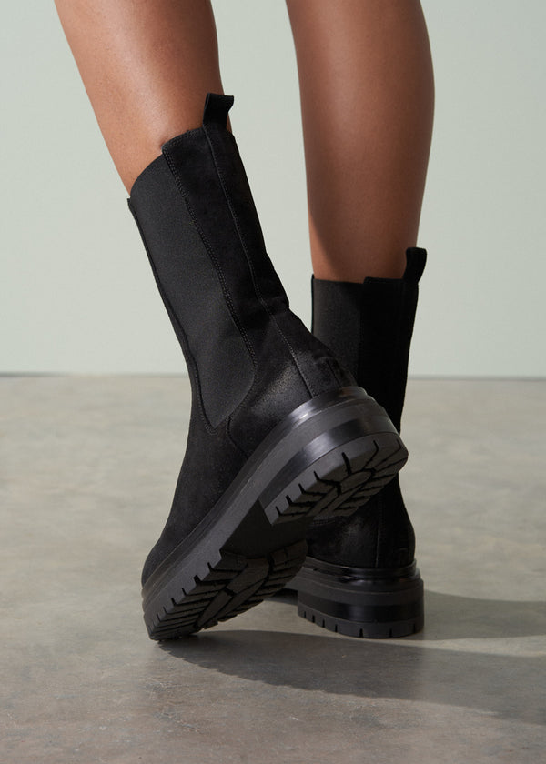 Black Chelsea boots on a neutral background