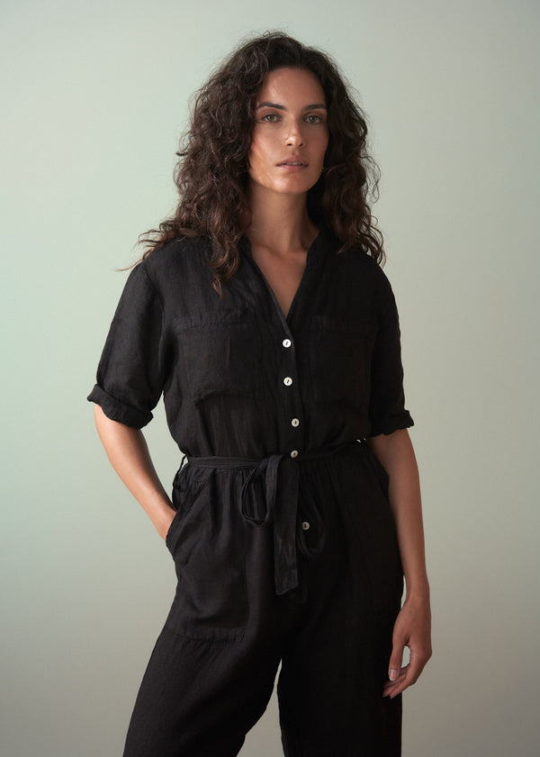 Woman wearing a black jumpsuit against a plain background