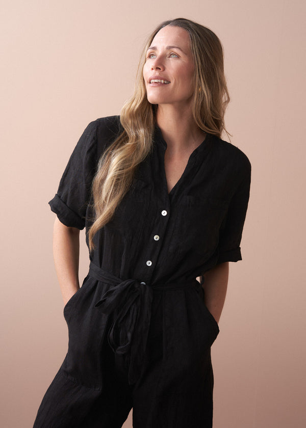 Woman wearing a black outfit against a beige background