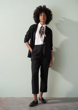 Person wearing a white shirt and black tapered trousers against a plain background