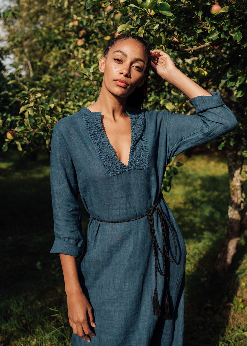 A model wearing a blue kaftan dress in an orchard