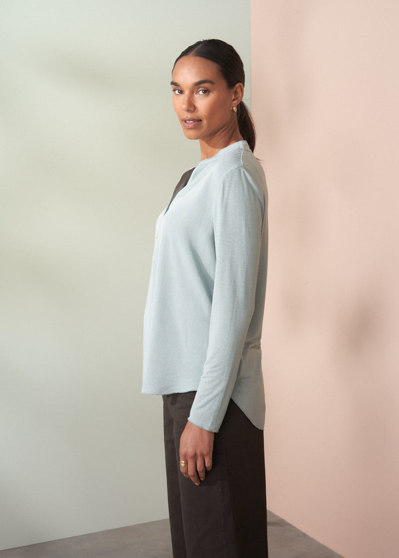 Woman wearing a light blue top against a plain background