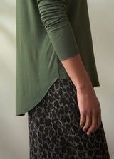 Person wearing a green top and leopard print skirt against a neutral background