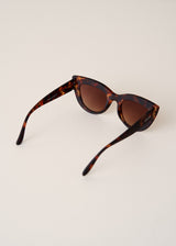 Brown tortoiseshell cat-eye sunglasses on beige background