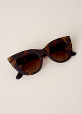 Brown tortoiseshell cat-eye sunglasses on beige background