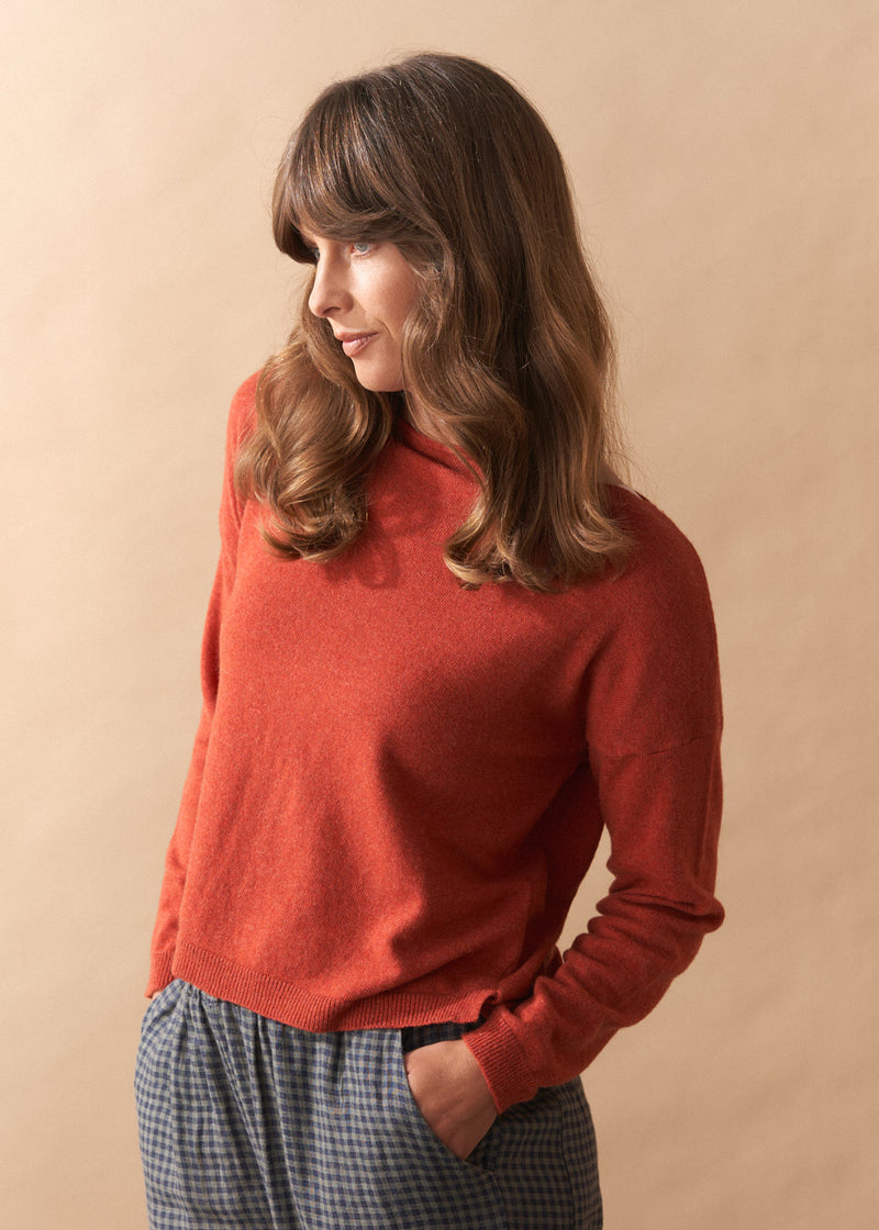 Woman wearing a red sweater against a beige background