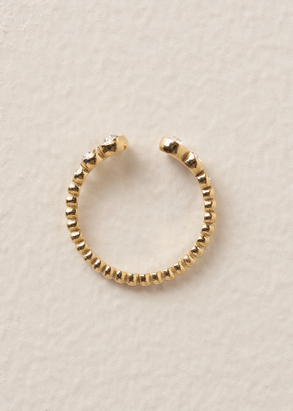 Gold minimal ring with clear crystals on a beige background