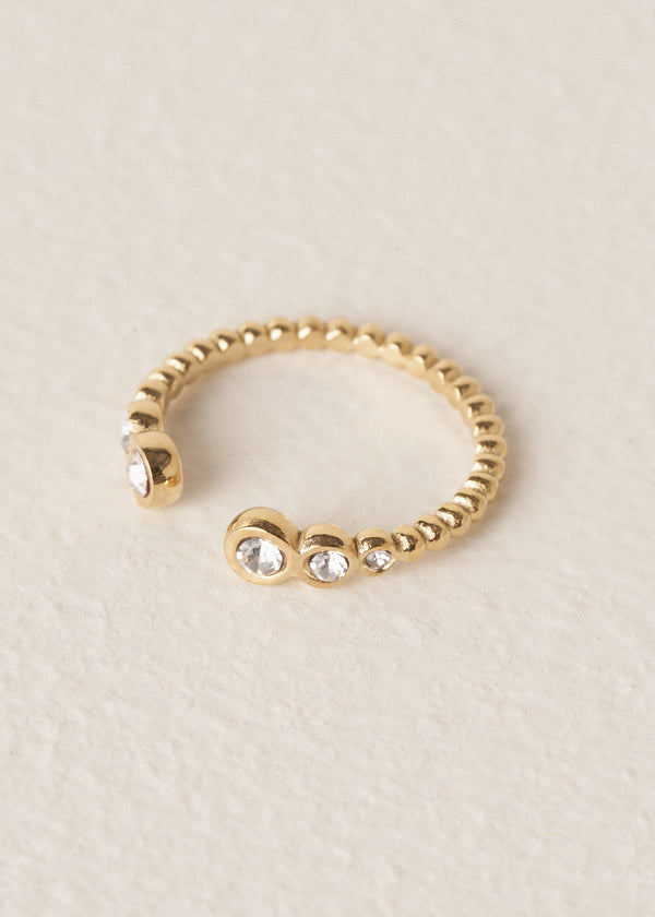 Gold minimal ring with clear crystals on a beige background