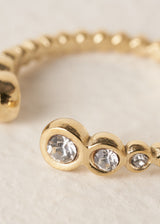 Gold minimal ring with clear crystals on a beige background