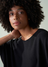 Woman wearing a black top against a neutral background