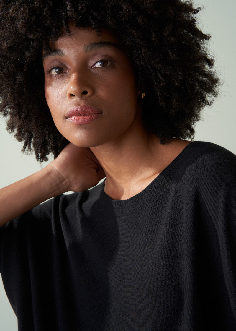 Woman wearing a black top against a neutral background