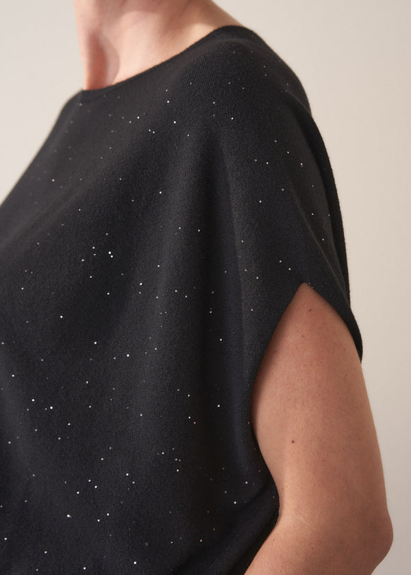 Black top with sequin detail worn by a person, on a neutral background