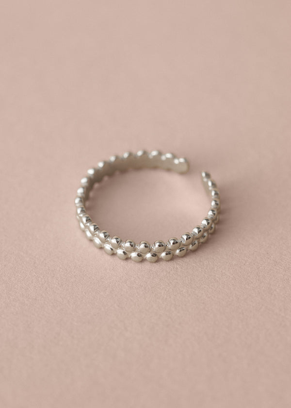 Silver beaded ring on a pink background