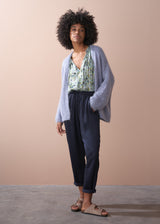 Women wearing a dusky lavender chunky oversized knit cardigan, with floral top and blue, drawstring trousers.