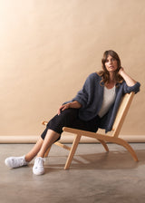 Woman sitting on a wooden chair against a beige wall