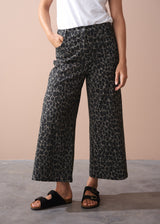 Person wearing khaki leopard print wide leg trousers on a beige background