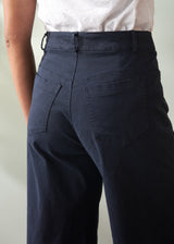 Navy blue wide leg trousers worn by a person on a plain background