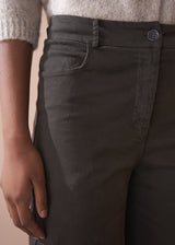 Person wearing dark brown wide-leg trousers and a beige cardigan against a plain background