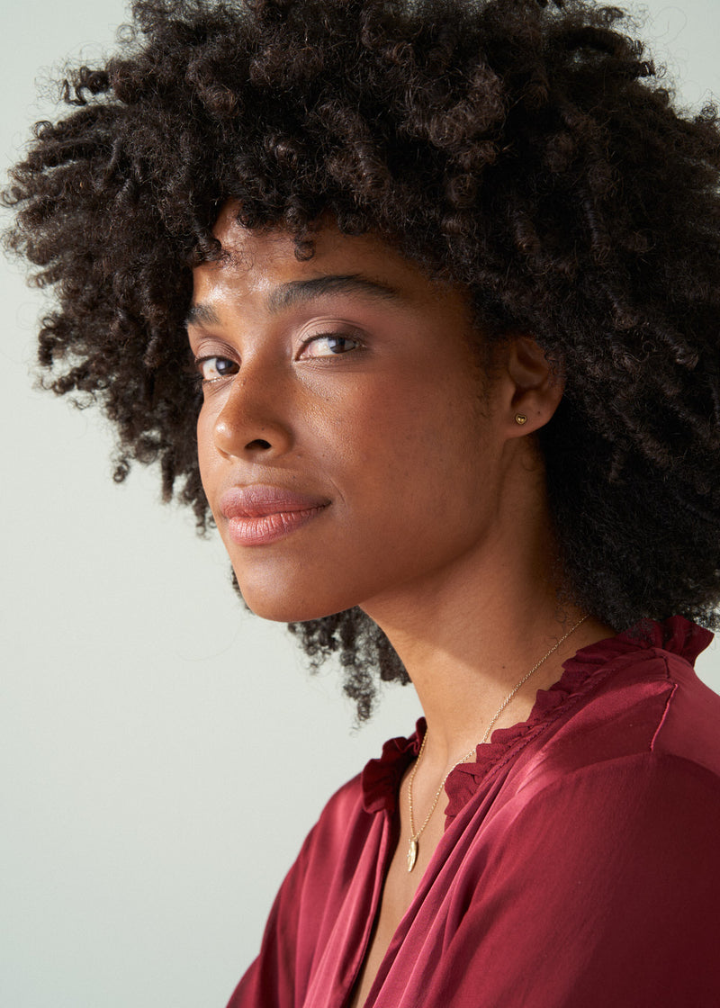 Woman wearing small gold heart stud earrings