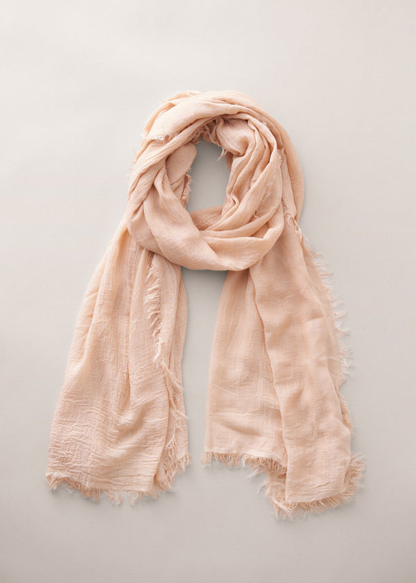 Light oatmeal scarf with frayed edges on a light gray background