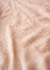 Light oatmeal scarf with frayed edges on a light gray background