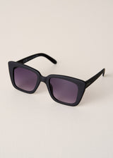 Black sunglasses with purple lenses on a beige background